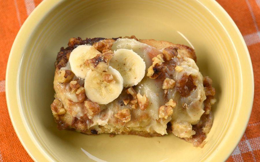 A banana espresso cinnamon roll topped with banana slices and walnuts