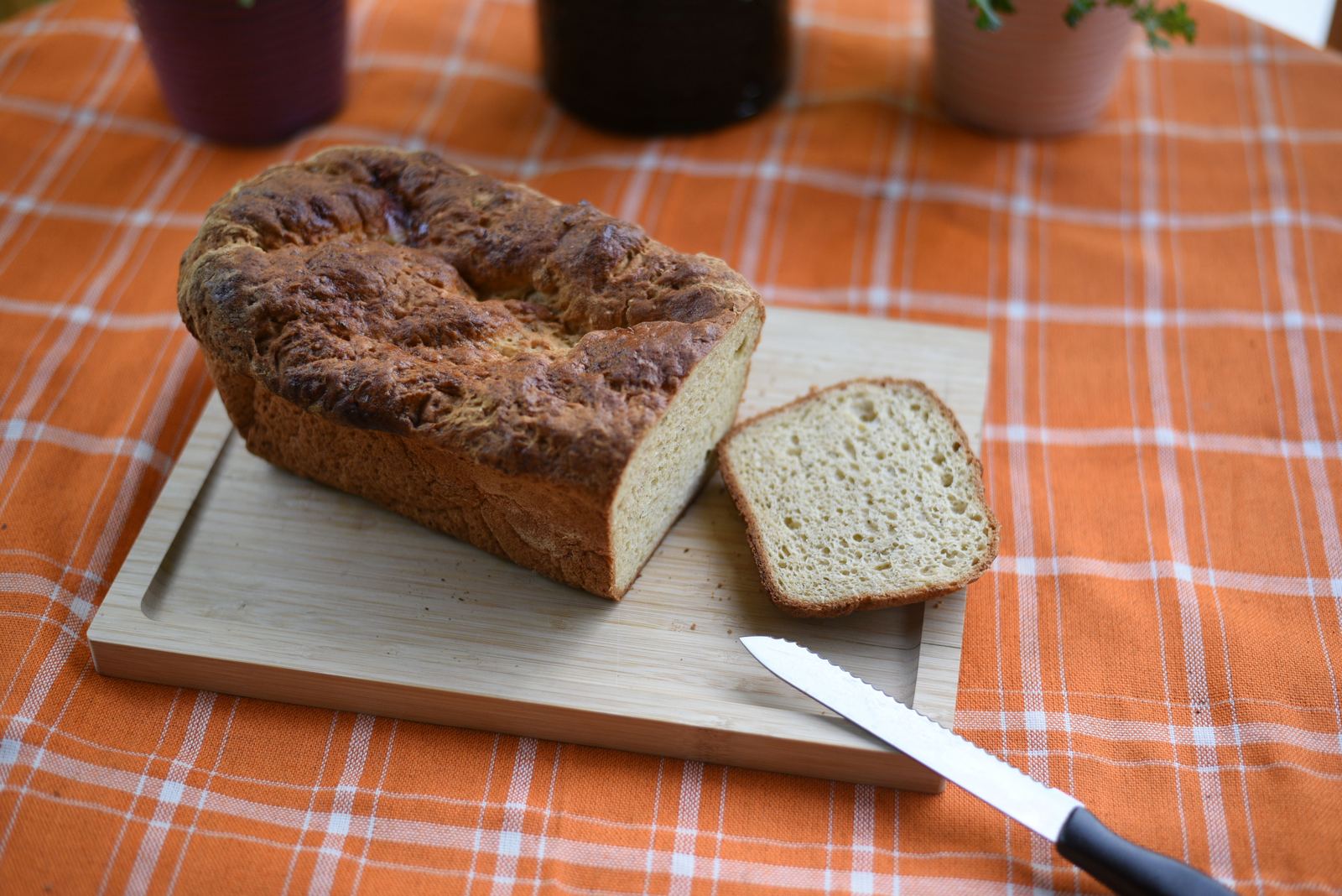 A golden loaf of gluten-free sandwich bread, sliced on a cutting board