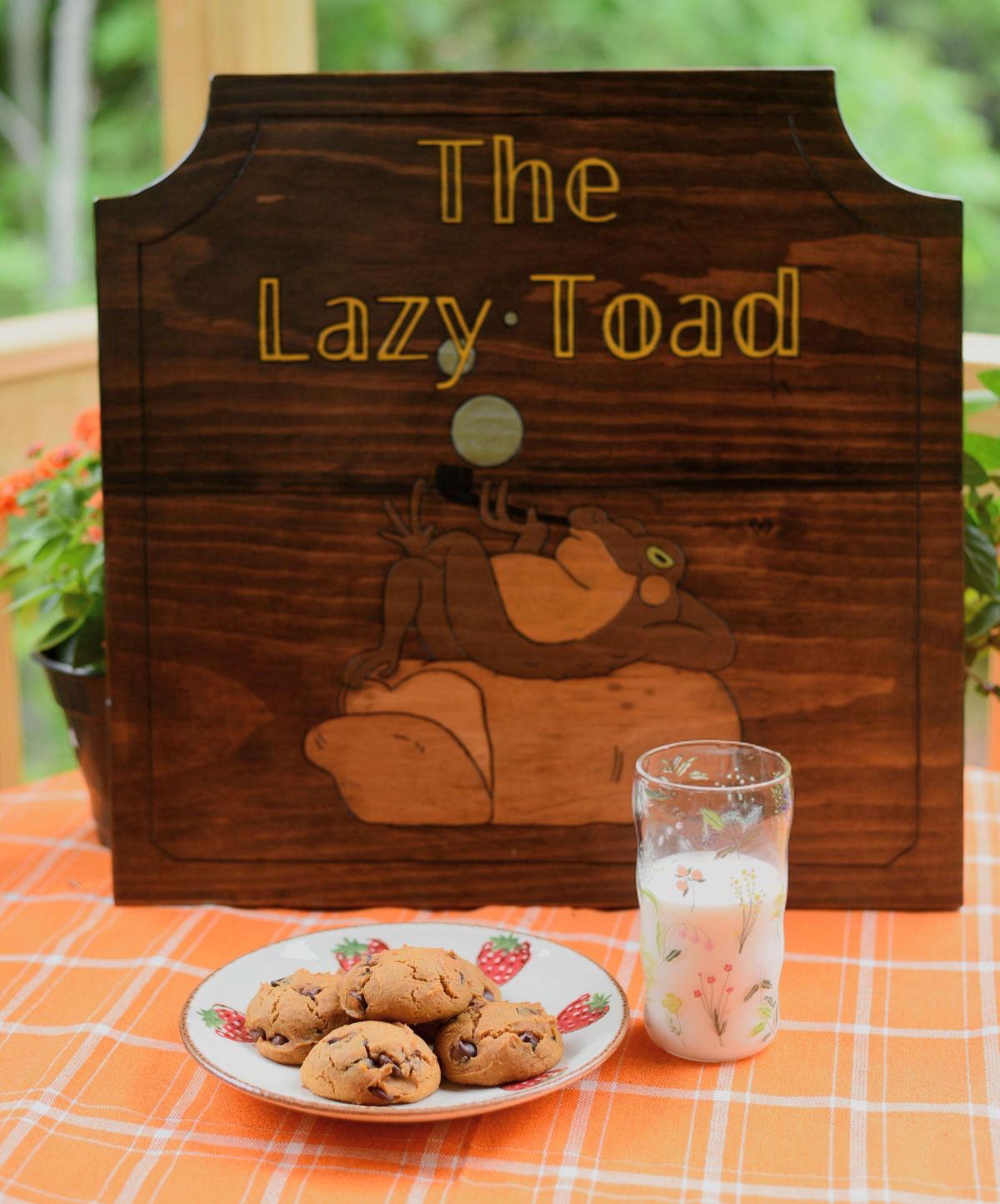 The Lazy Toad wooden sign behind a plate of cookies and a glass of milk